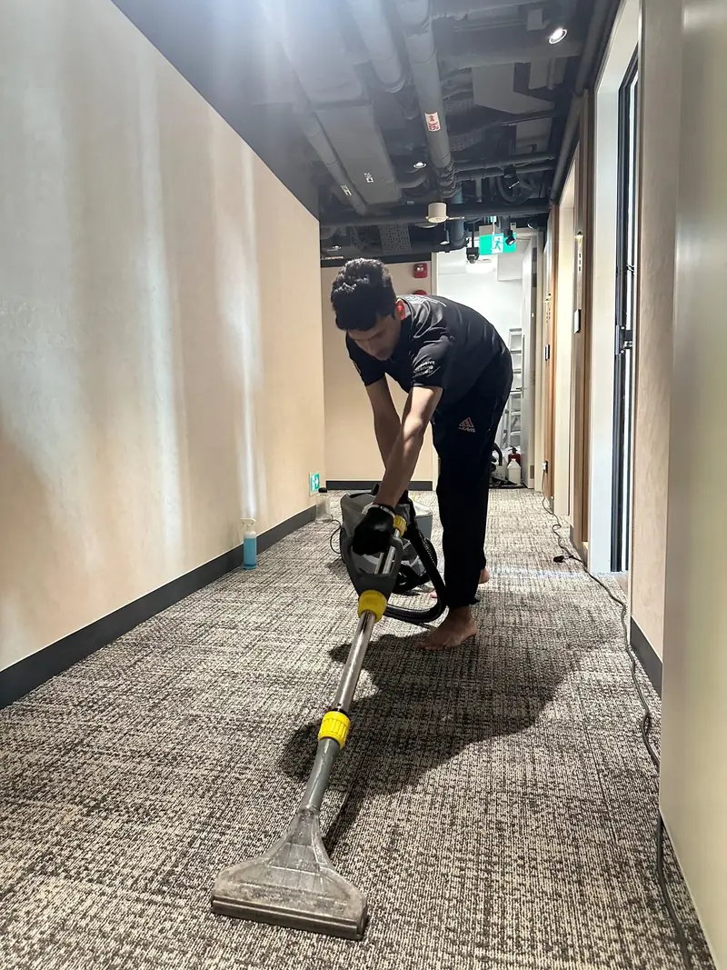 An OCD cleaner vacuuming a corridor carpet